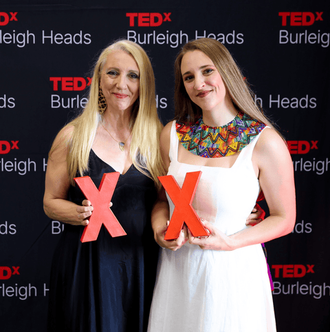 TEDx Relmi and Silvia Damiano holding red 'X' signs in front of a TEDx Burleigh Heads backdrop